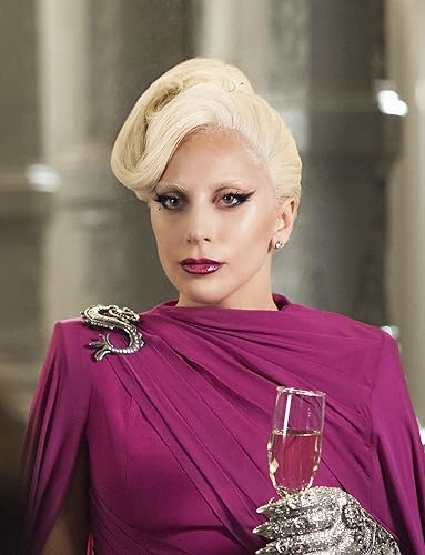 Lady Gaga in a purple cloak holding a wineglass